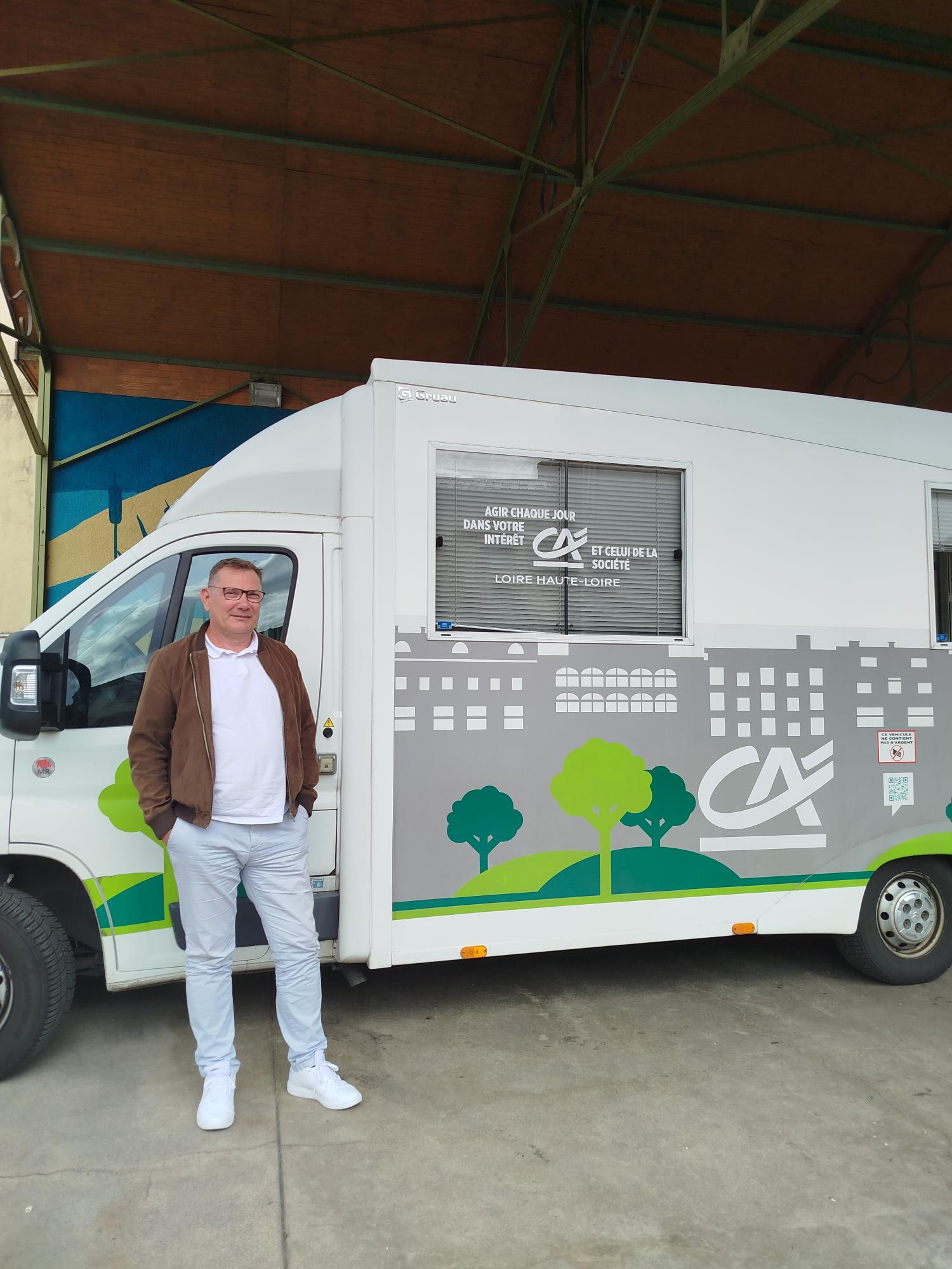 Le conseiller devant le camion-agence du Crédit Agricole, garé sous la halle