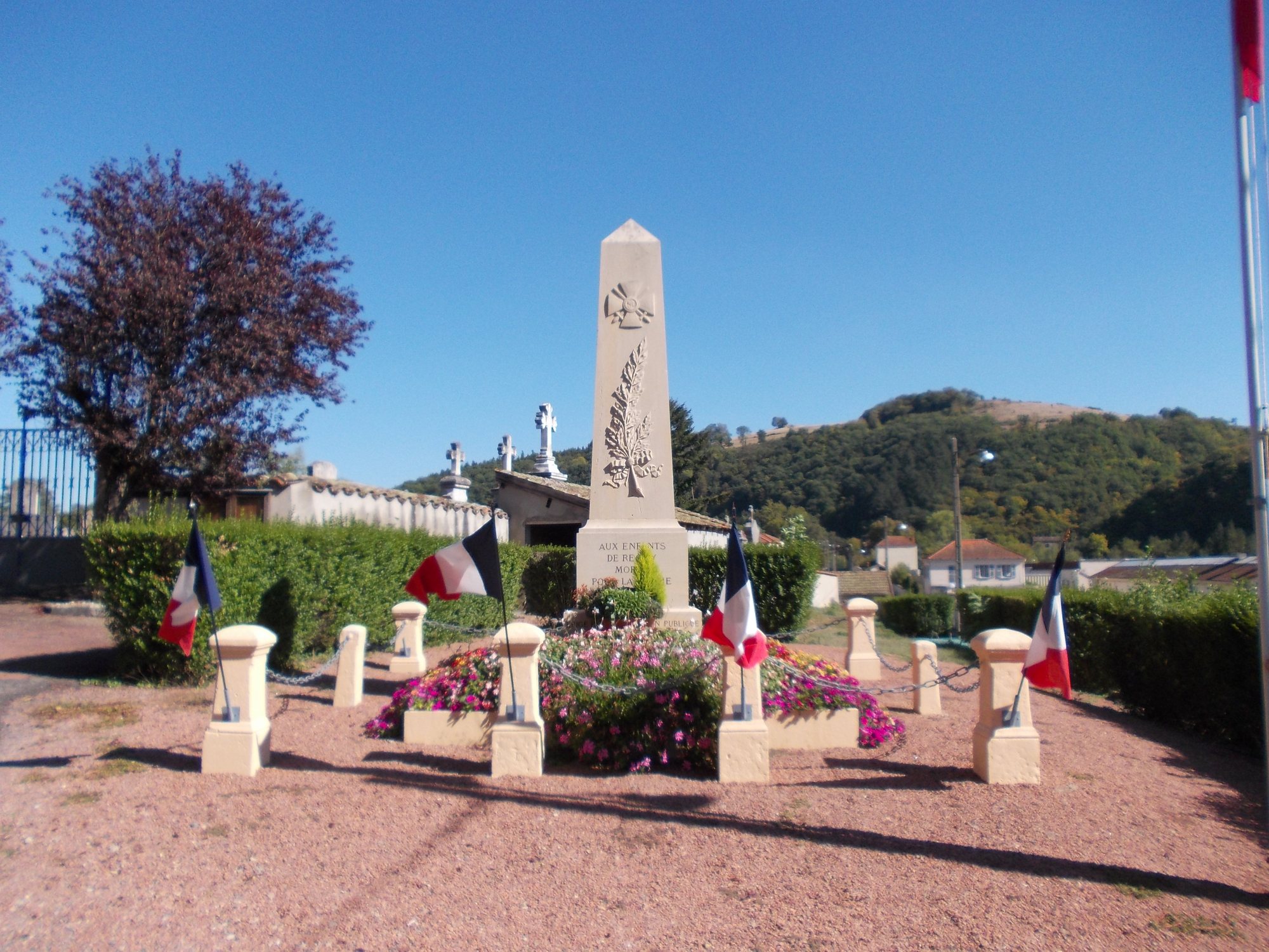 Le monument aux morts, fleuri, drapeaux tricolores